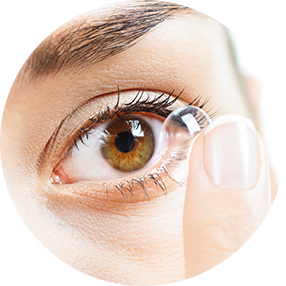 In einem braunen Auge wird eine Kontaktlinse mit einem Finger eingesetzt.